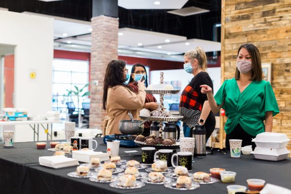 dessert table with people standing around eating and talking